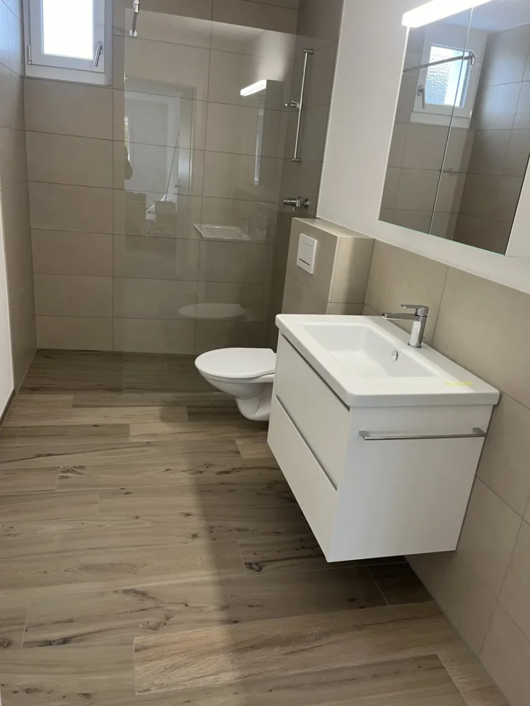 Beiges Bad mit Glasdusche, Wand-WC und Holzoptik-Boden