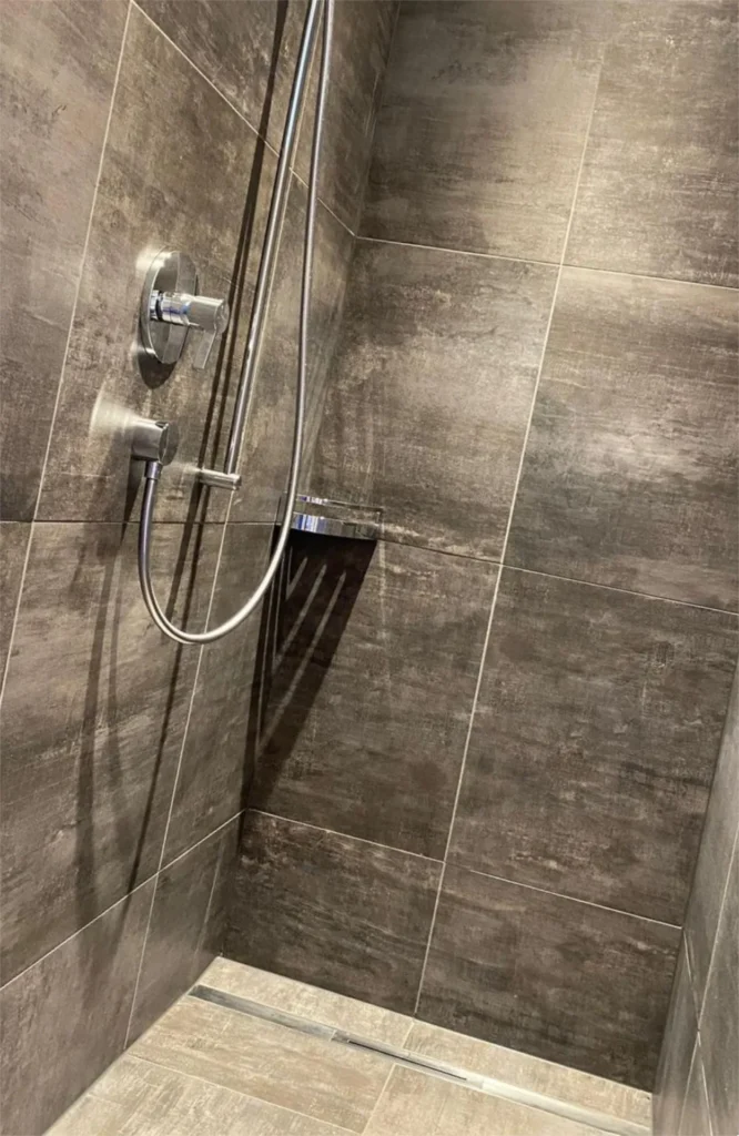 Bodengleiche Dusche in dunkler Betonoptik mit Edelstahl-Duschrinne