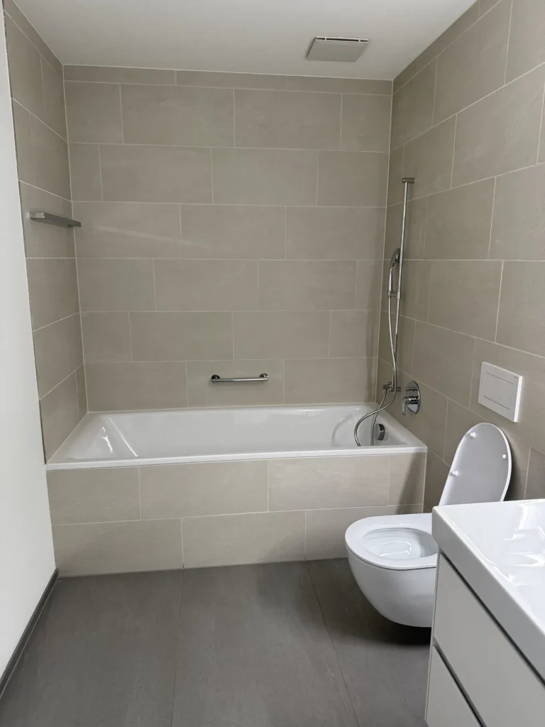 Eingefliesste Badewanne in Beige mit anthrazitfarbenem Grossformat-Boden