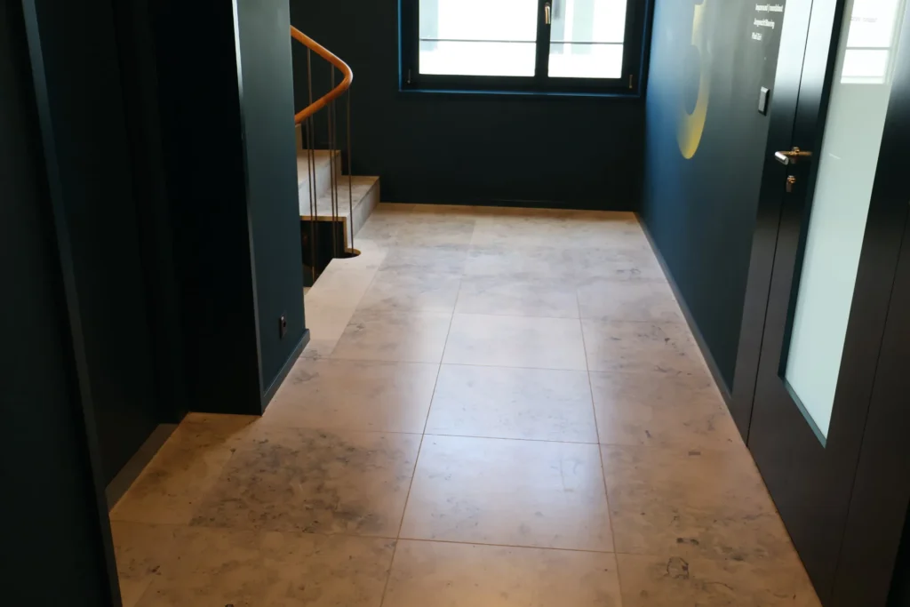 Etagenflur mit grossformatigen Natursteinplatten und Treppenaufgang