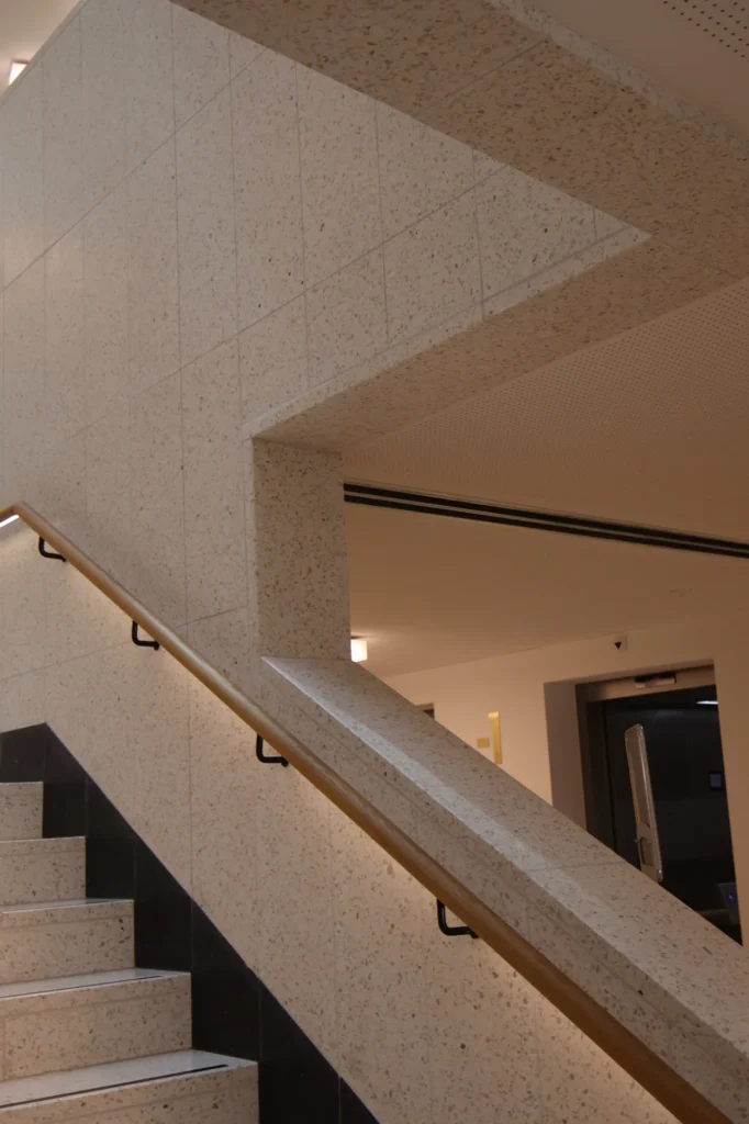 Detail Treppenwange und Wandverkleidung aus hellem Terrazzo-Kunststein