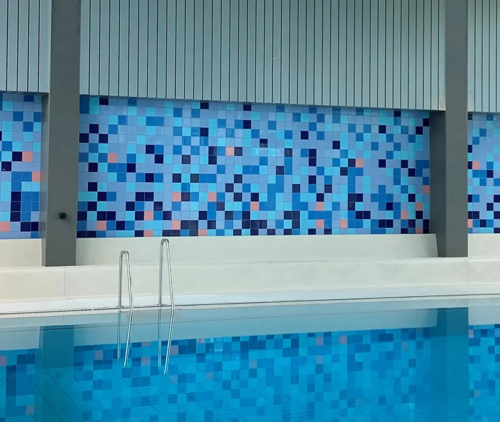 Blaues Streumosaik über Schwimmbecken mit Edelstahl-Einstiegsleiter