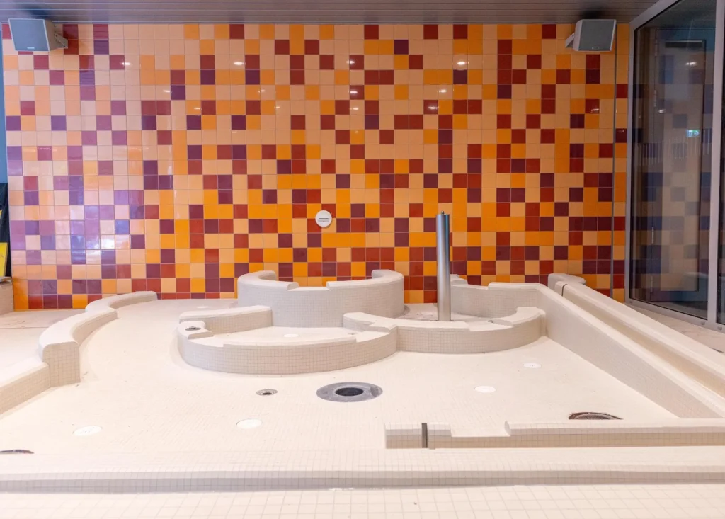 Whirlpool mit warmem Orange-Rot-Mosaik und weissem Mosaik-Beckenkörper