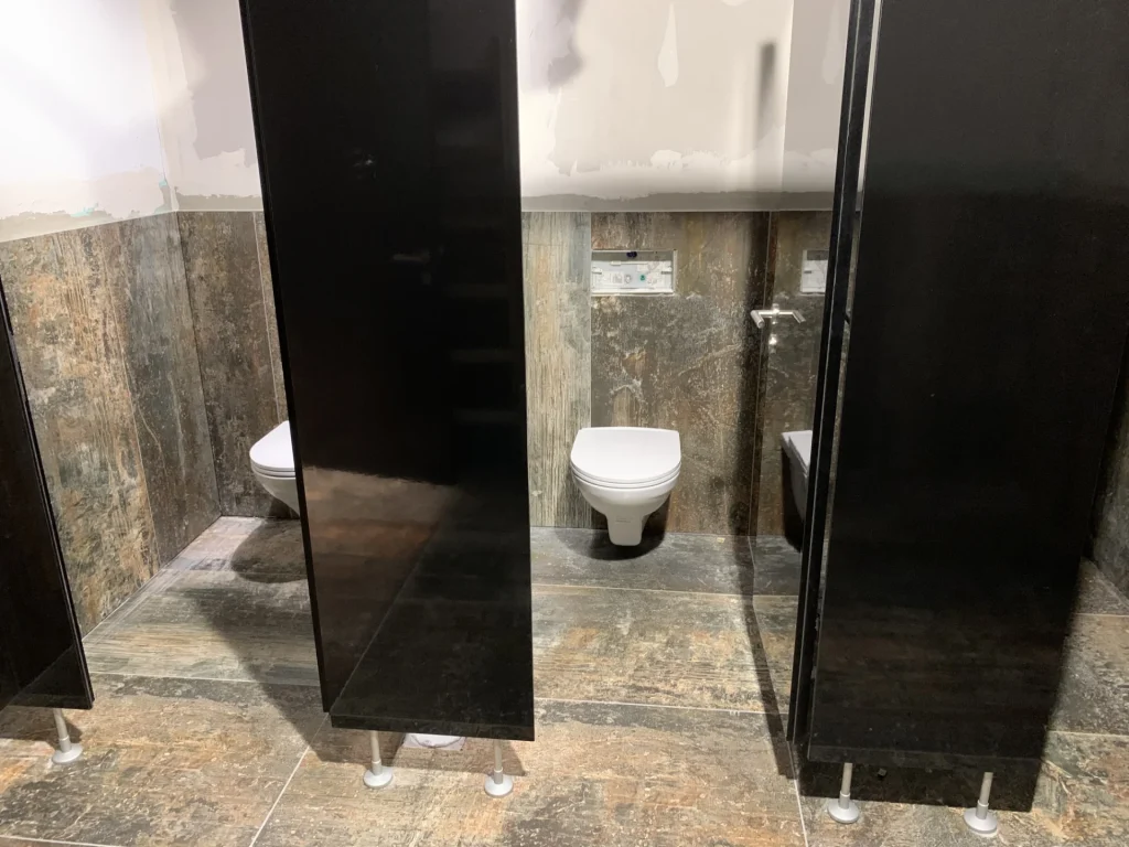 WC-Bereich mit dunklem Metall-Optik-Feinsteinzeug und schwarzen Trennwänden