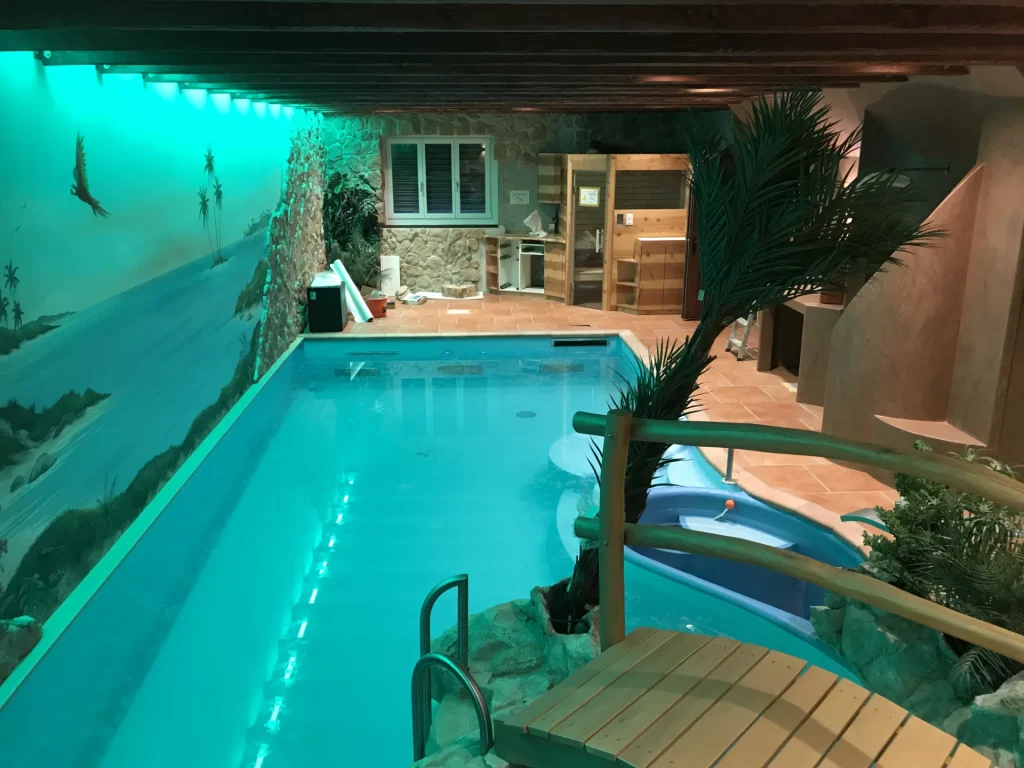 Beleuchteter Innenpool mit Sauna und Wasserrutsche