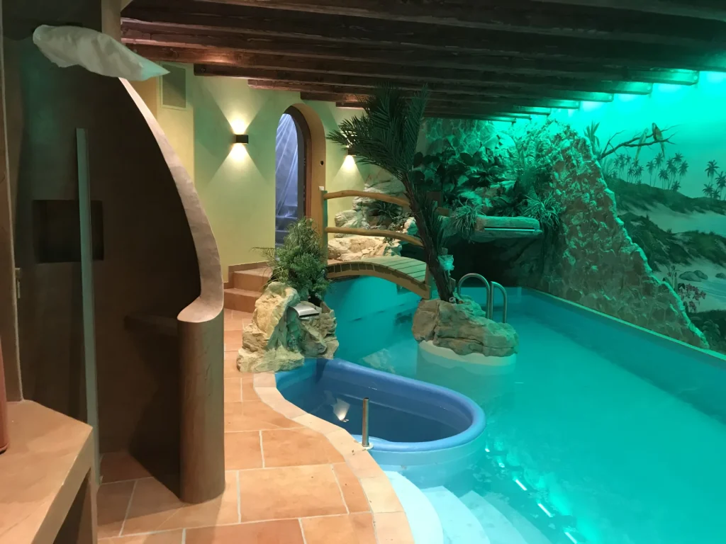 Grotten-Whirlpool mit Rundbogen und Palmen im Wellnessbereich