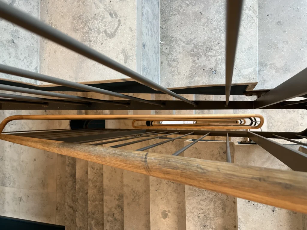 Detailaufnahme Treppenauge mit Holzhandlauf und Natursteinstufen