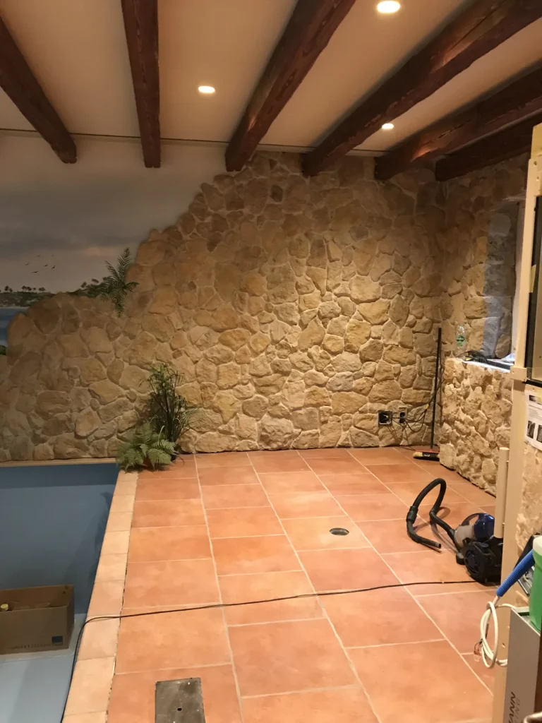 Terrakotta-Bodenfliesen und Natursteinwand am Beckenrand