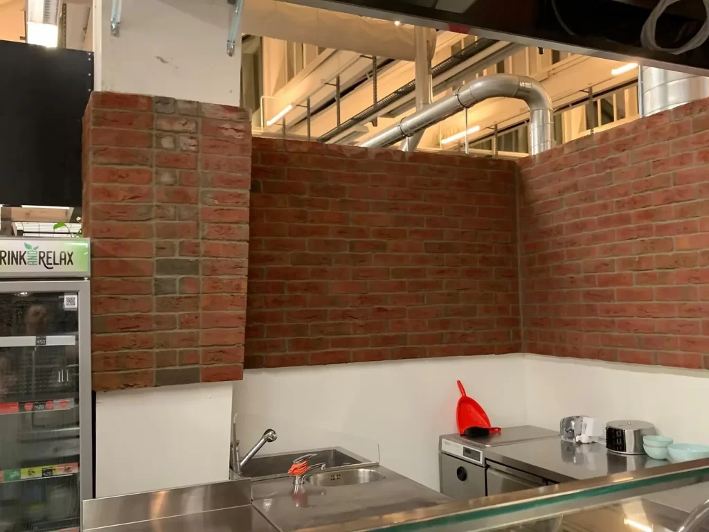 Küchenrückwand aus roten Klinker-Riemchen über Edelstahl-Spüle mit dunklen Fugen