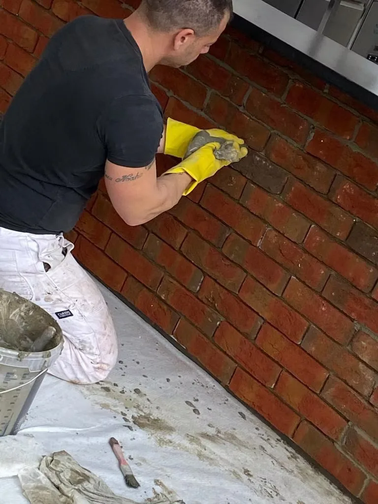 Plattenleger verfugt rote Backstein-Riemchen an der Küchenwand von Hand
