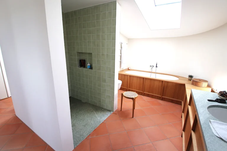 Grosses Bad mit Terrakotta-Boden, Badewanne und salbeigrüner Duschnische