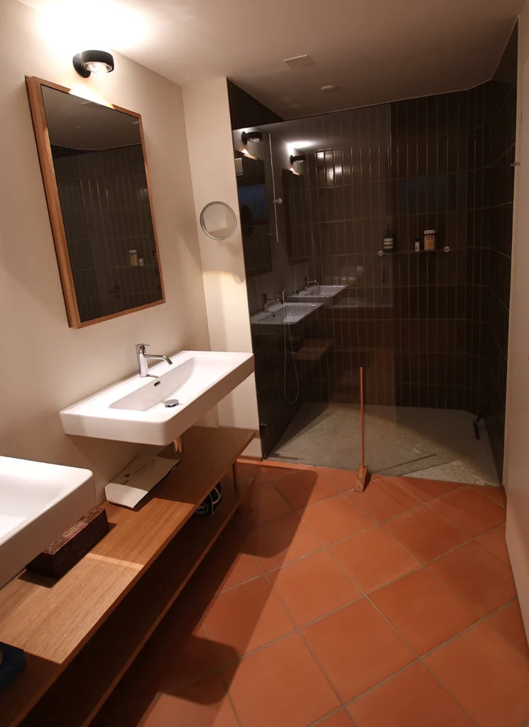 Begehbare Dusche in dunklen Keramik-Riemchen mit Terrakotta-Boden
