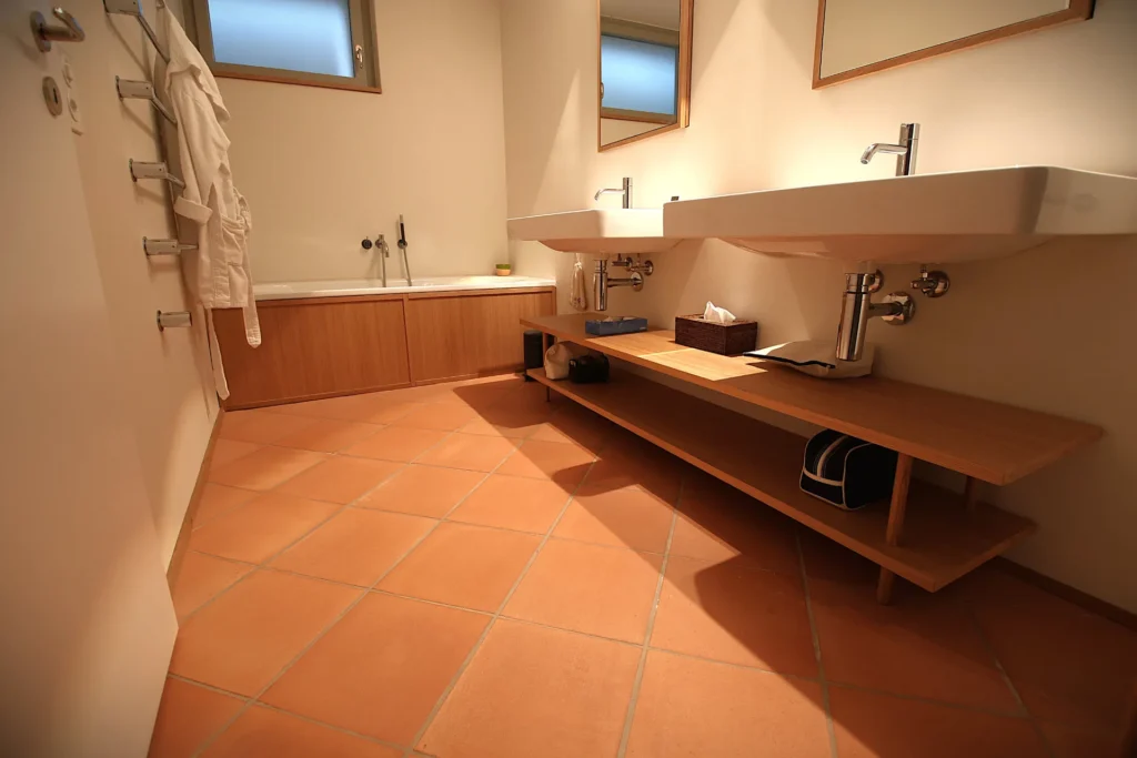 Badezimmer mit Terrakotta-Boden, Doppelwaschtisch und Badewanne aus Eiche