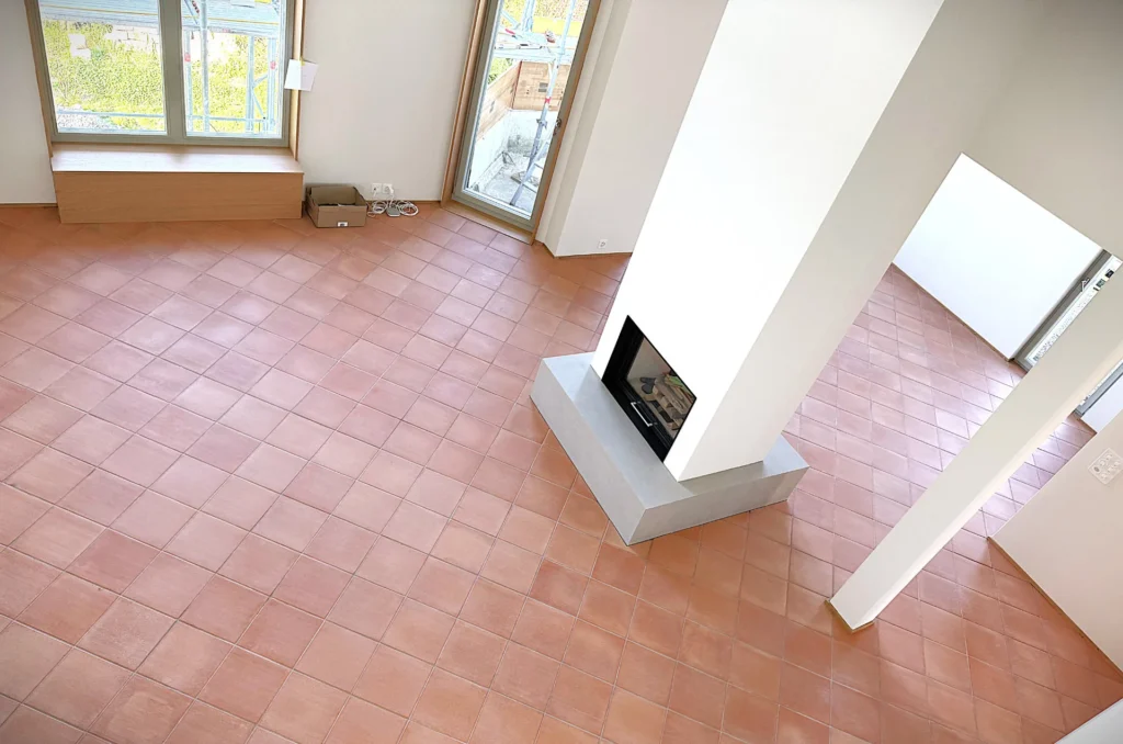 Grosser Wohnraum mit hellem Terrakotta-Boden und Cheminée im Rohbau
