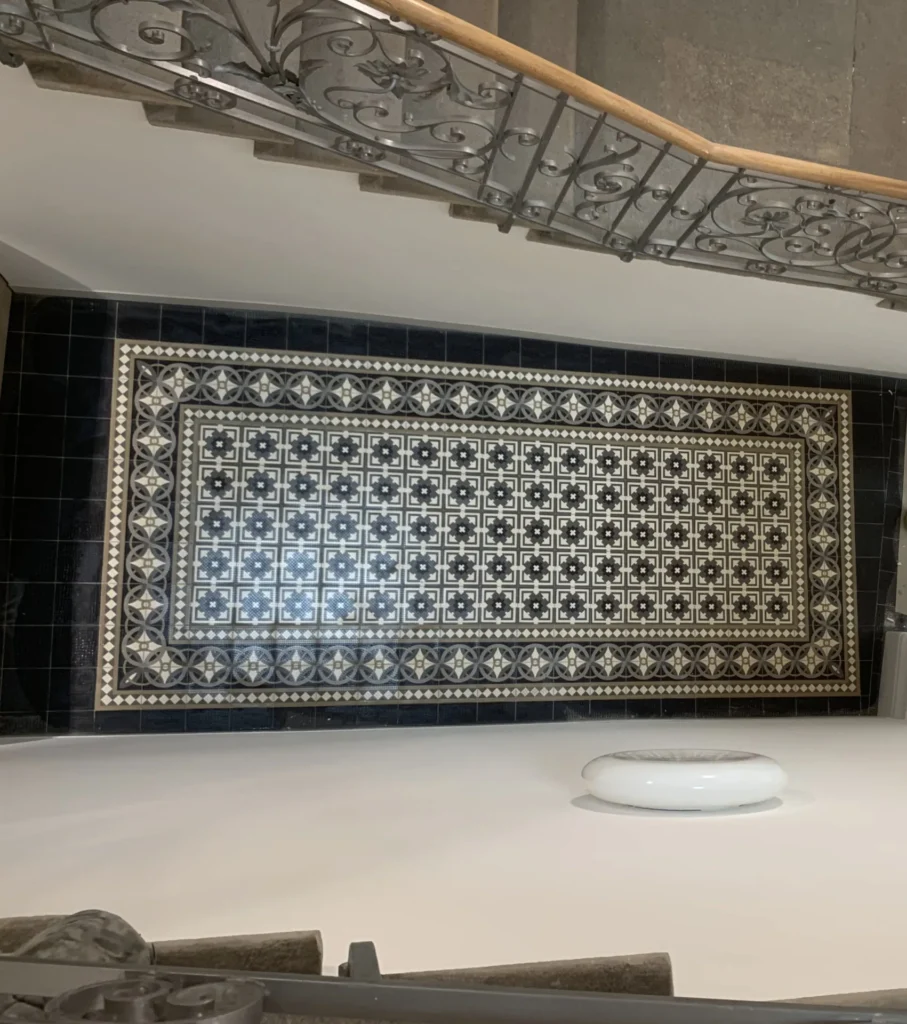 Historisches Zementmosaik-Feld unter schmiedeeiserner Treppe