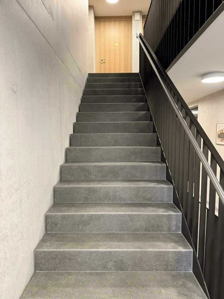 Feinsteinzeug-Treppe in Betonoptik mit schwarzem Metallgeländer
