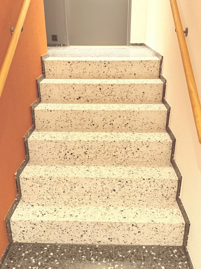 Beige Terrazzo-Treppe mit Setzstufen im privaten Treppenhaus