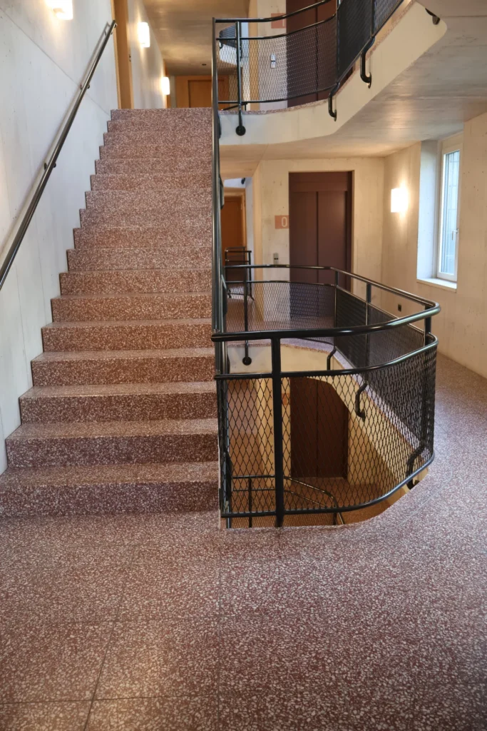 Roter Terrazzo-Antritt mit gewölbtem Podest und Metallgeländer