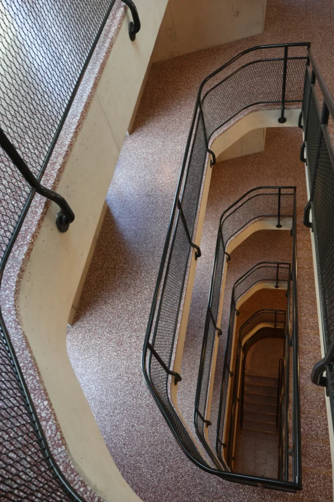 Roter Terrazzo im Altbau-Treppenhaus mit schwarzem Gittergeländer